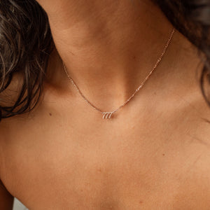 Model wearing rose gold Nayru Name Necklace featuring numbers on the nameplate