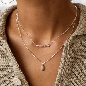 Model wearing silver Nayru Name Necklace, layered with a silver pendant necklace