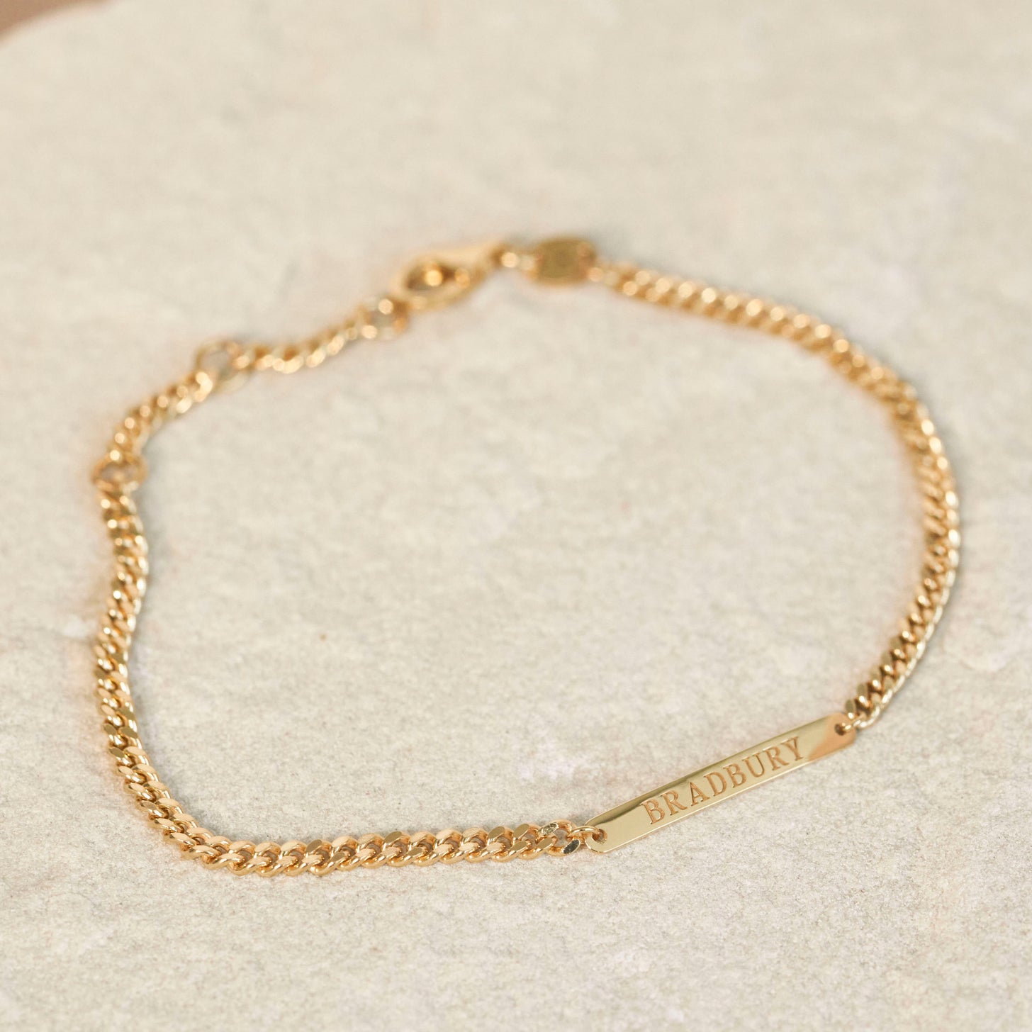 The Darcy Bracelet featuring a curb chain and engraved bar with surname