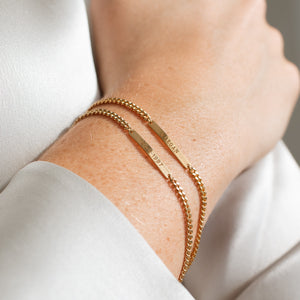 Model wearing two Darcy Bracelets by Grace Personalized featuring engraved names and dates
