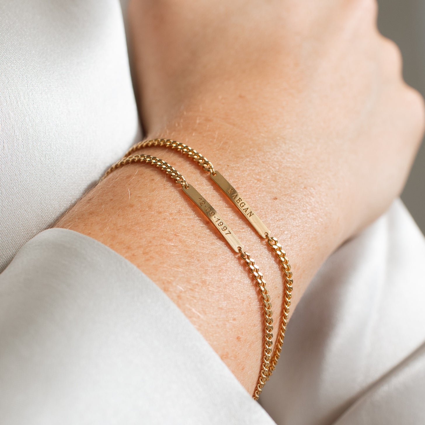 Model wearing two Darcy Bracelets by Grace Personalized featuring engraved names and dates