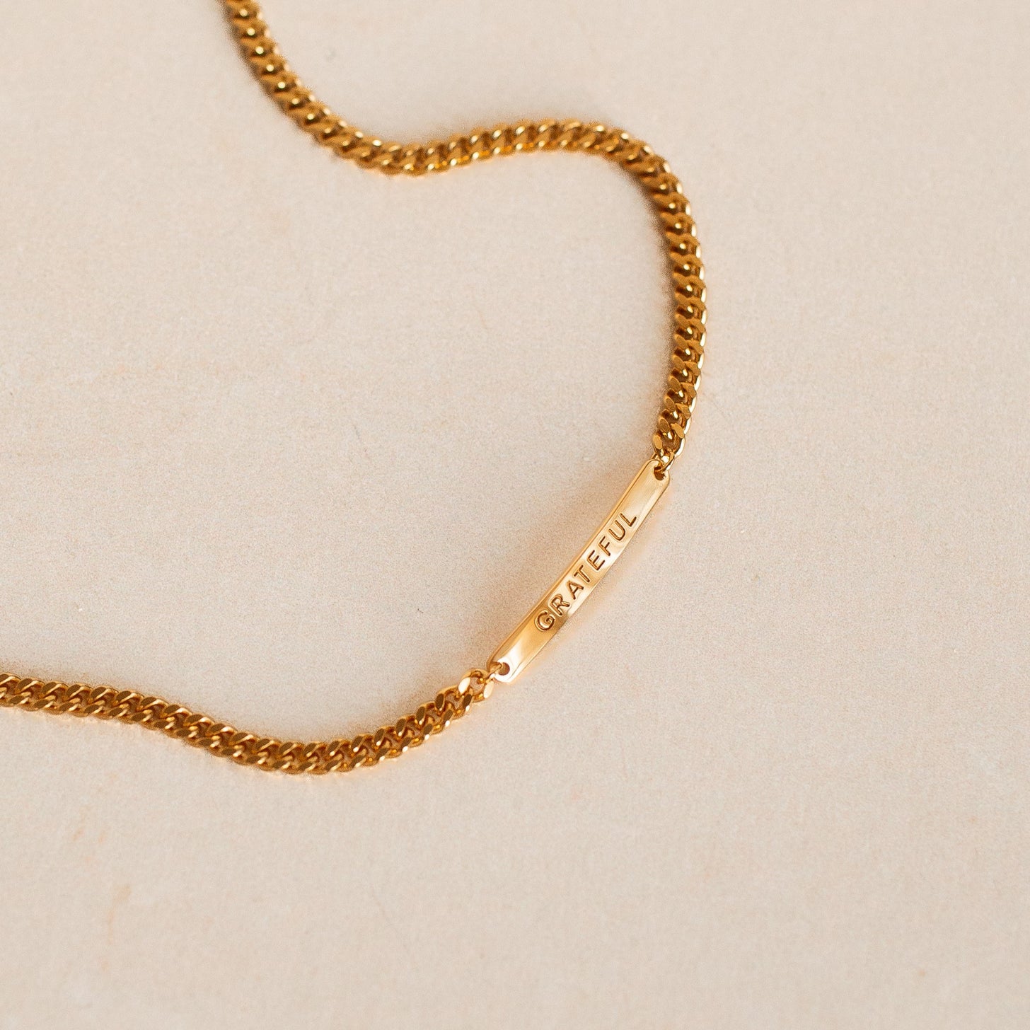 A gold engraved bar bracelet with a meaningful word
