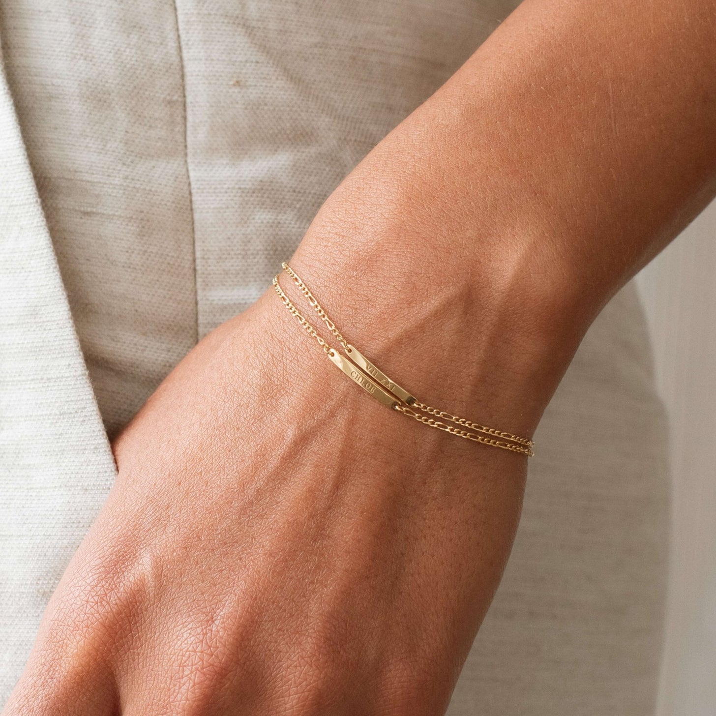 Model wearing two Dayne Engraved Bar Bracelets in gold
