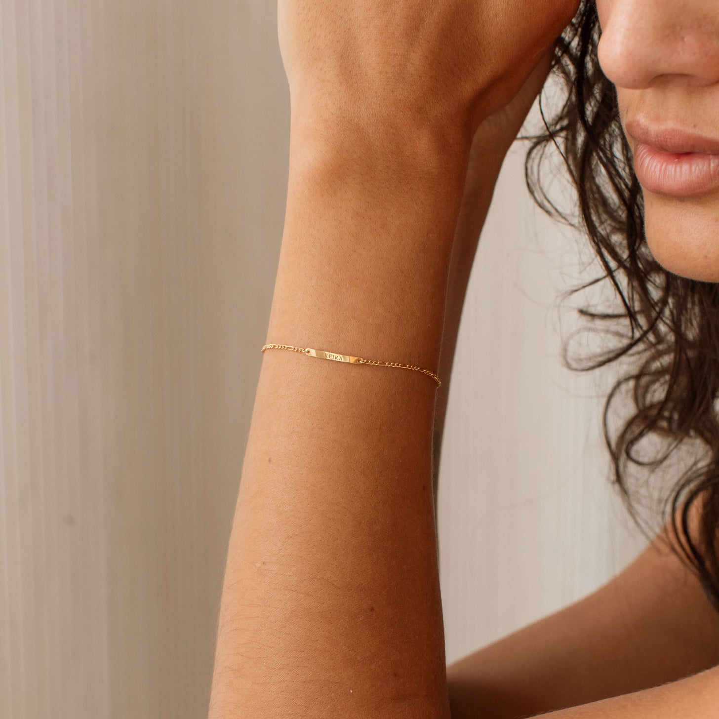 Model wearing a dainty bar bracelet with a custom name engraving