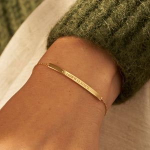 Custom engraved coordinates and message on a dainty gold bar bracelet