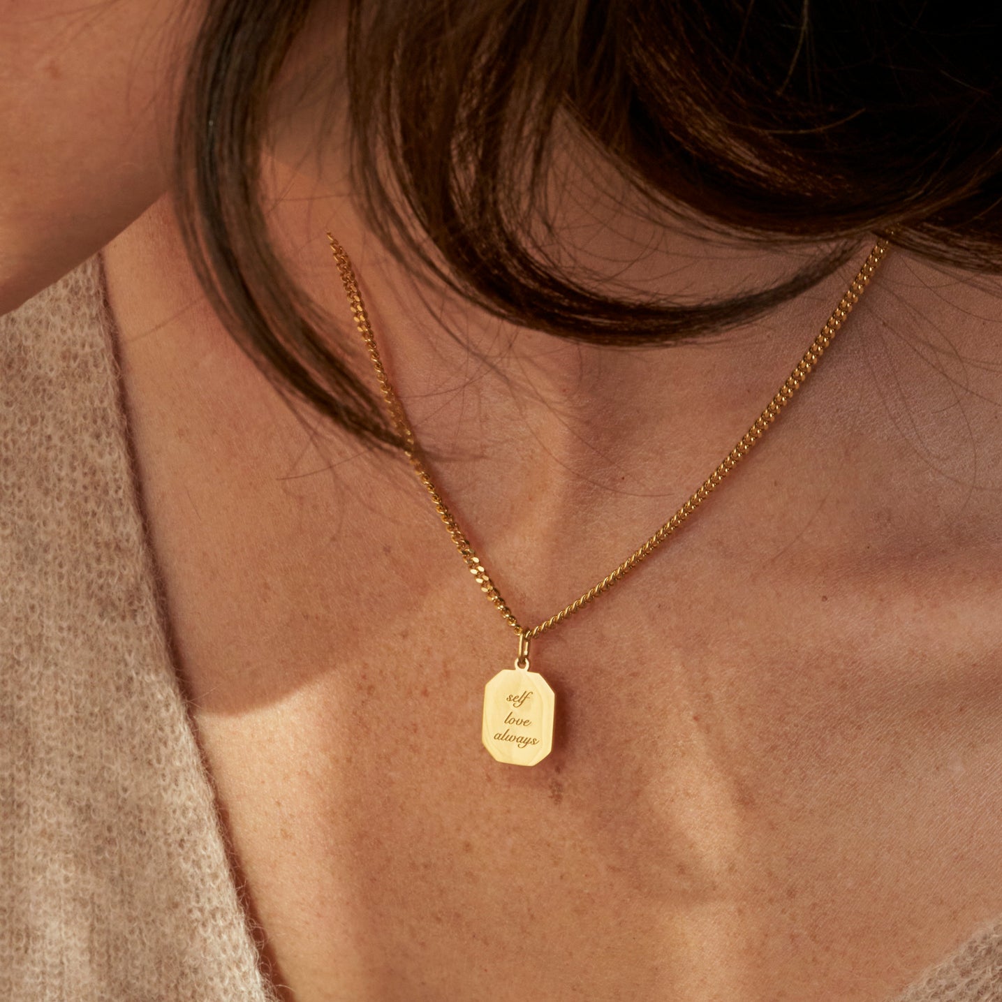 Custom engraved affirmations, phrases, and messages on a gold dog tag pendant necklace, featuring a bold curb chain