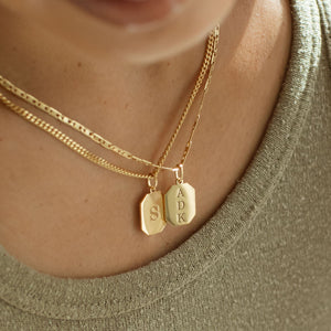 Gold dog tag pendant necklaces with custom engraved initials in a modern font