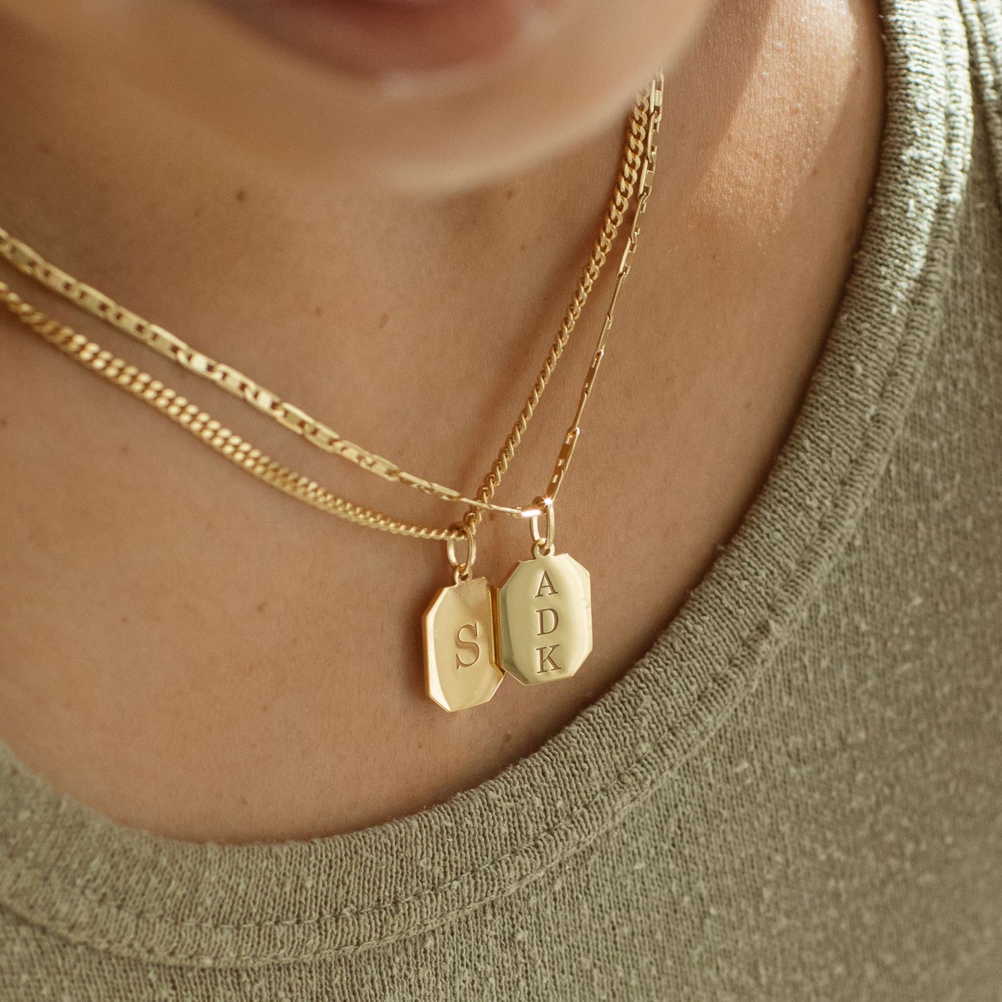 Gold dog tag pendant necklaces with custom engraved initials in a modern font