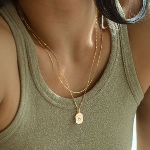Custom initial engraved on a pendant necklace in a dog tag shape, with a gold mini link chain