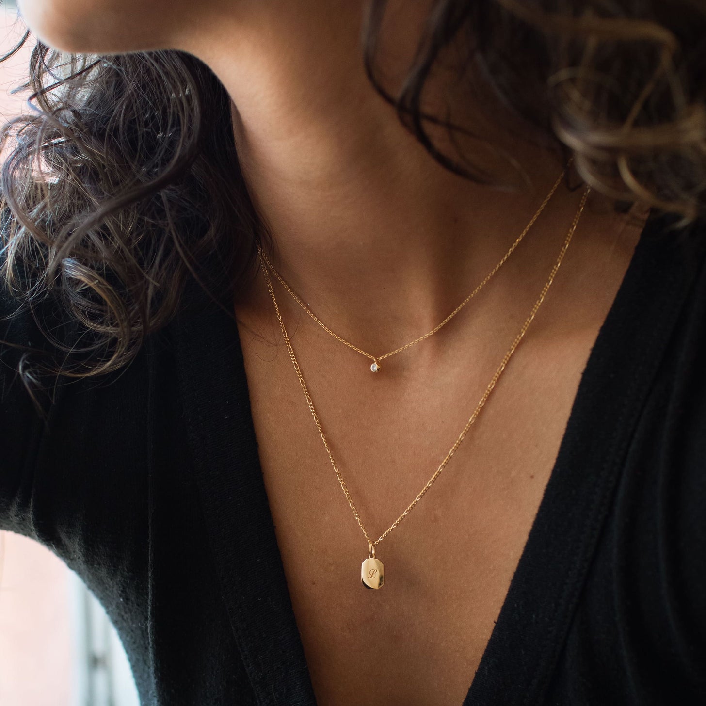 Custom engraved initial in an elegant script font on a gold dog tag pendant necklace