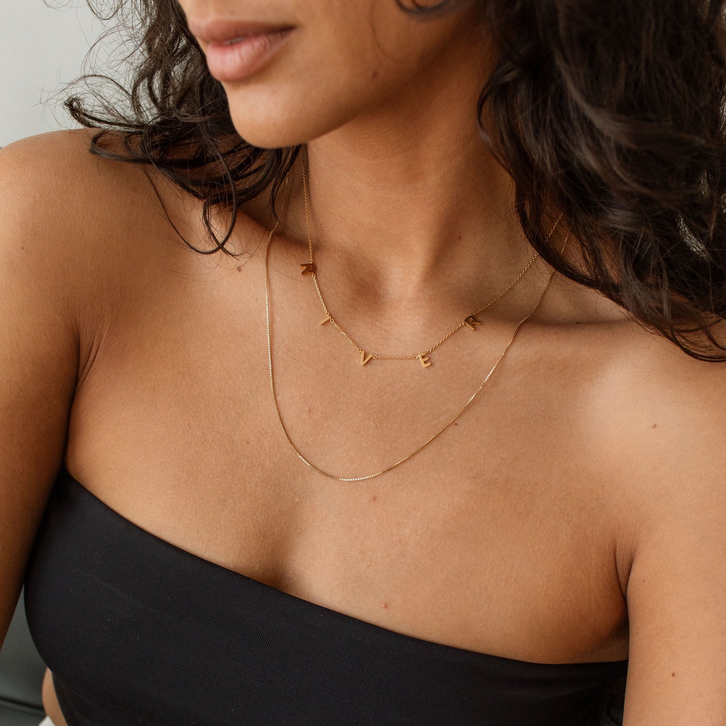 Model wearing gold custom Name Necklace layered with a fine chain
