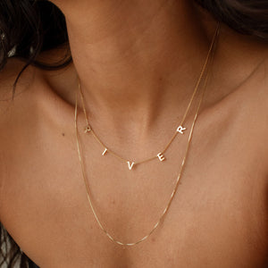 Model wearing gold custom Name Necklace layered with a fine chain
