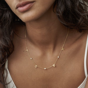4 initial letters and 3 cubic zirconia stones along a dainty chain necklace