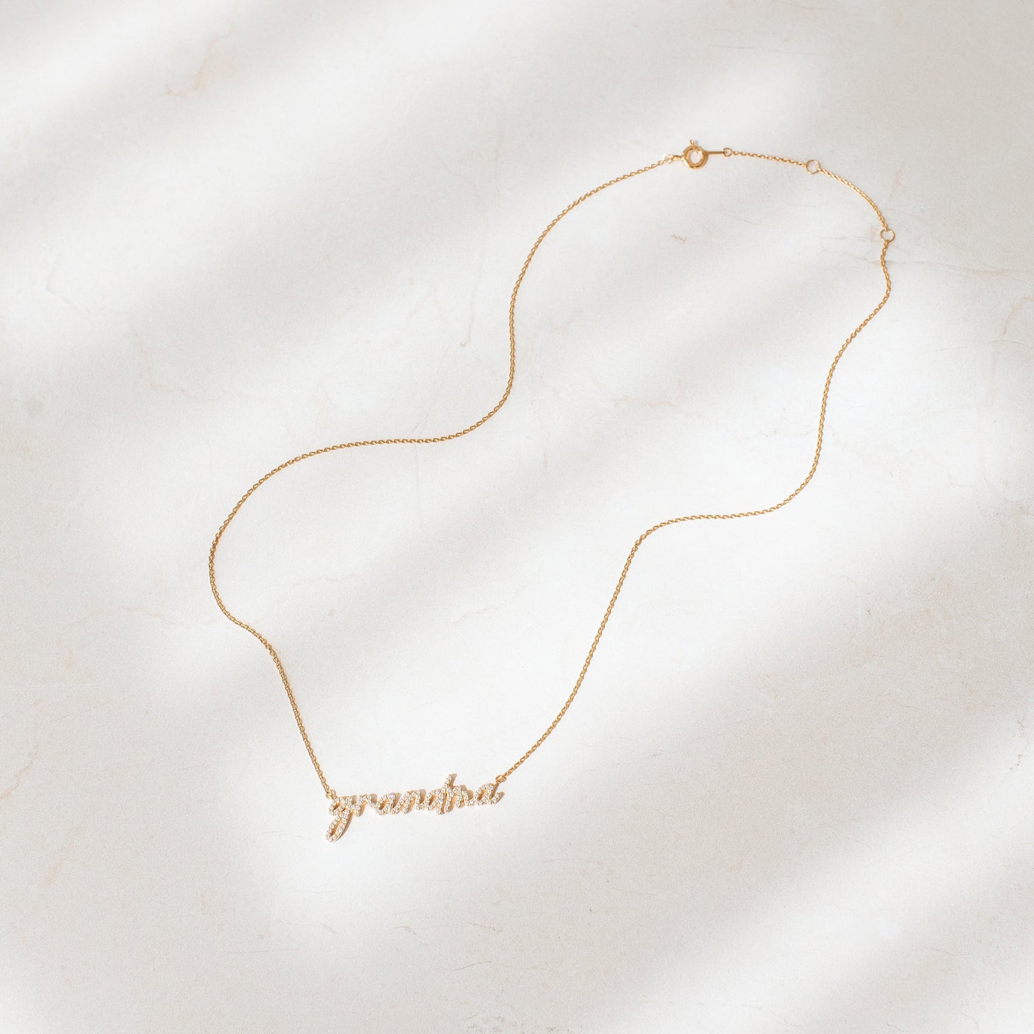 Mother's Day gift for grandma with CZ stones and 'grandma' handwritten in a script font on a dainty gold chain