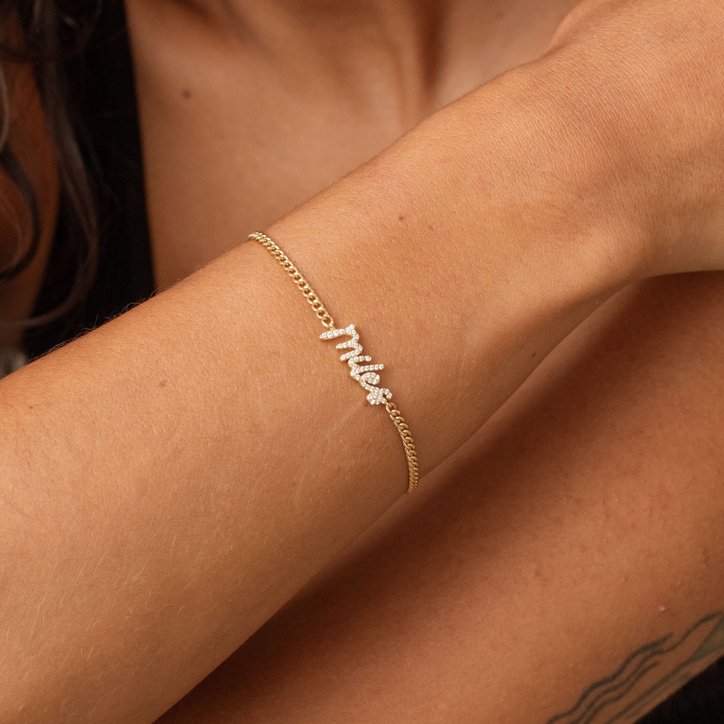 Model wearing custom name bracelet with pave script letters and curb chain