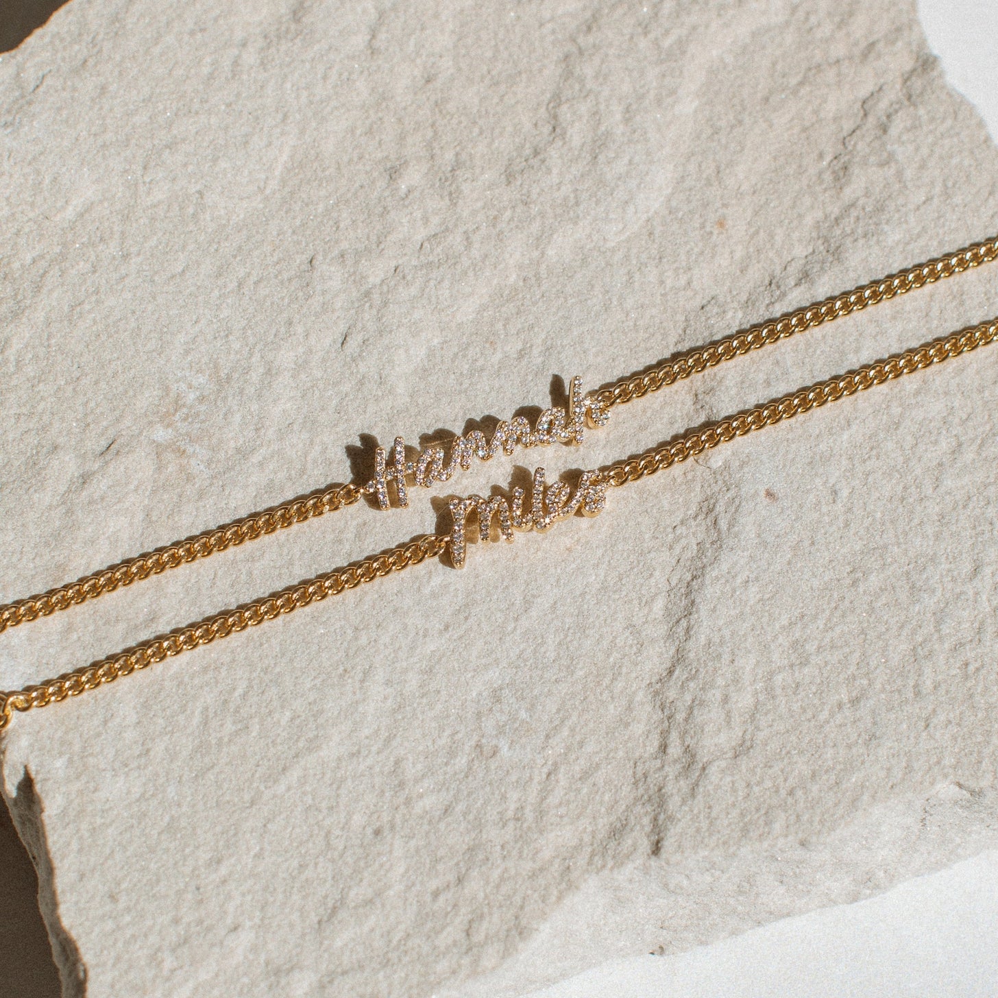 2 examples of Naia Pave Name Bracelet with script letters and curb chain