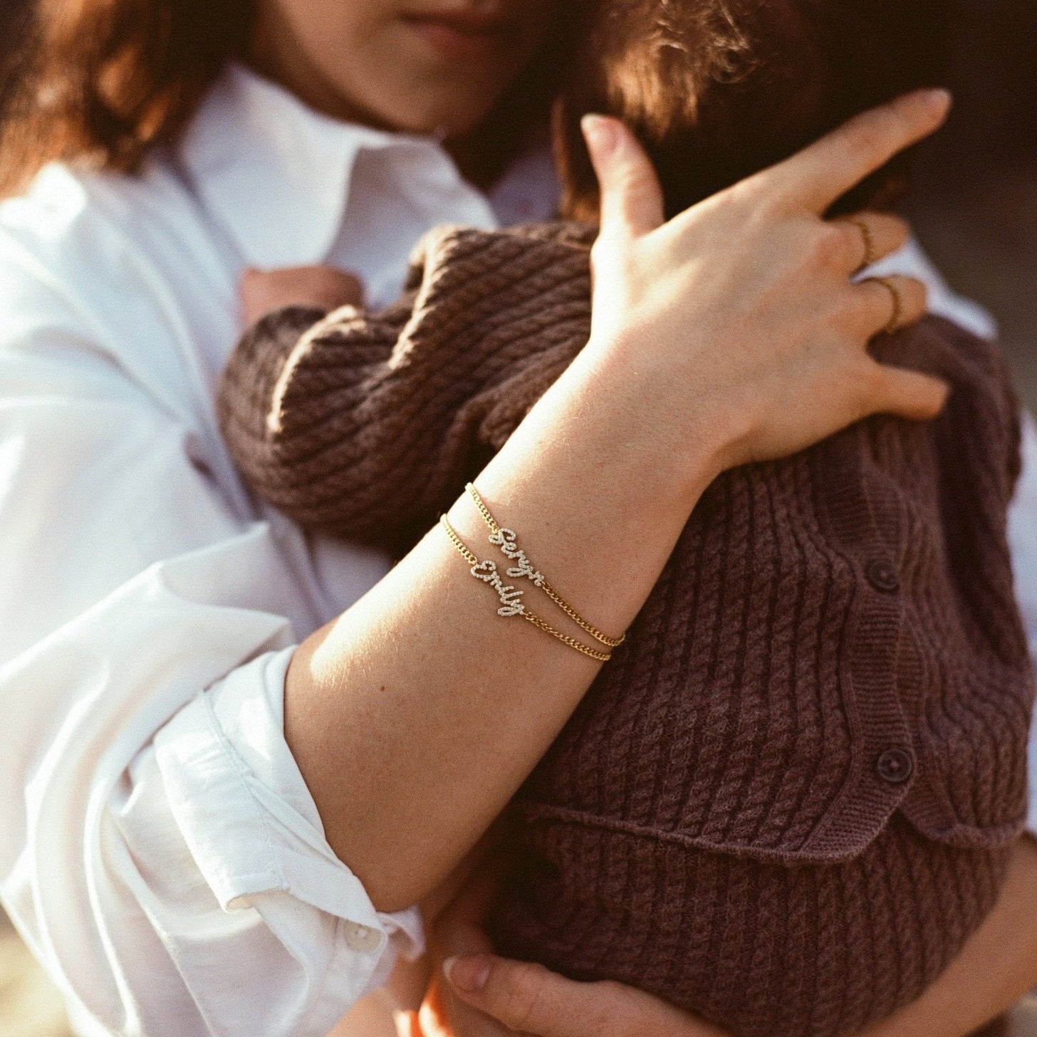 Woman holding baby wearing 2 Naia Pave Name Bracelets