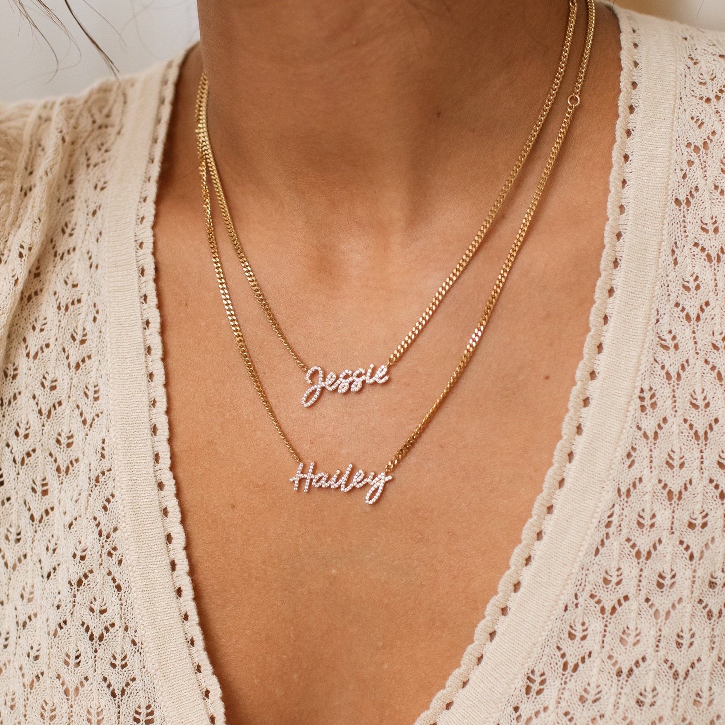 Model wearing 2 gold Naia Pave Name Neckalces