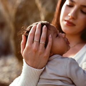 Mother holding baby wearing Naia Name Rings studded in cubic zirconia stones