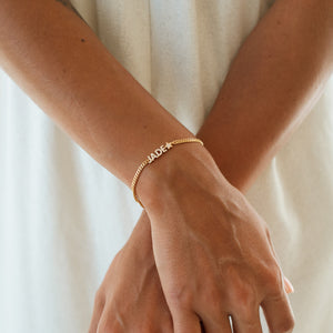 Model wearing a gold Nancy Name Bracelet with pave letters