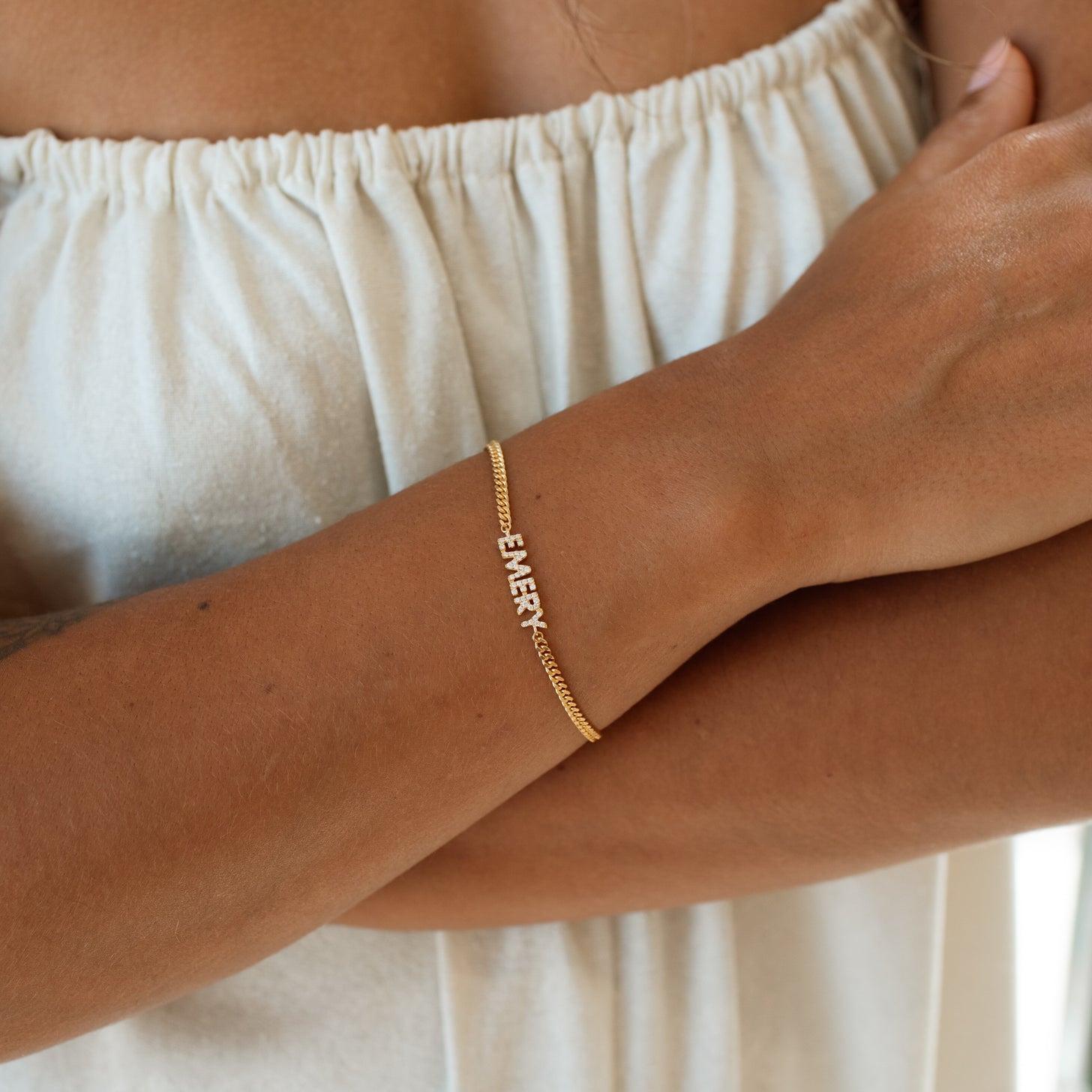 Model wearing a gold pave name bracelet with curb chain