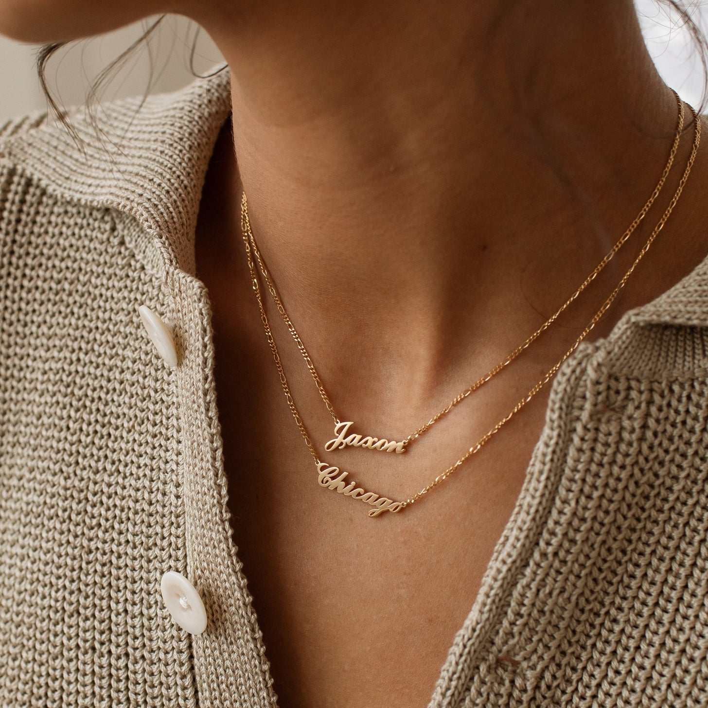 Model wearing 2 gold Nayru Name Necklaces with sweater
