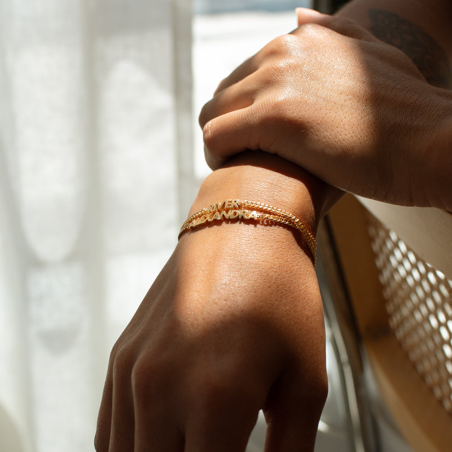 Model wearing two gold Nelly Name Bracelets
