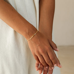Model wearing a gold custom name bracelet with modern font
