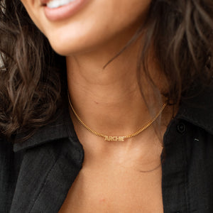 Model wearing a gold Nelly Name Necklace with black button down shirt