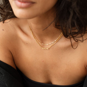 Model wearing gold Nelly Name Necklace layered with mariner anchor chain necklace