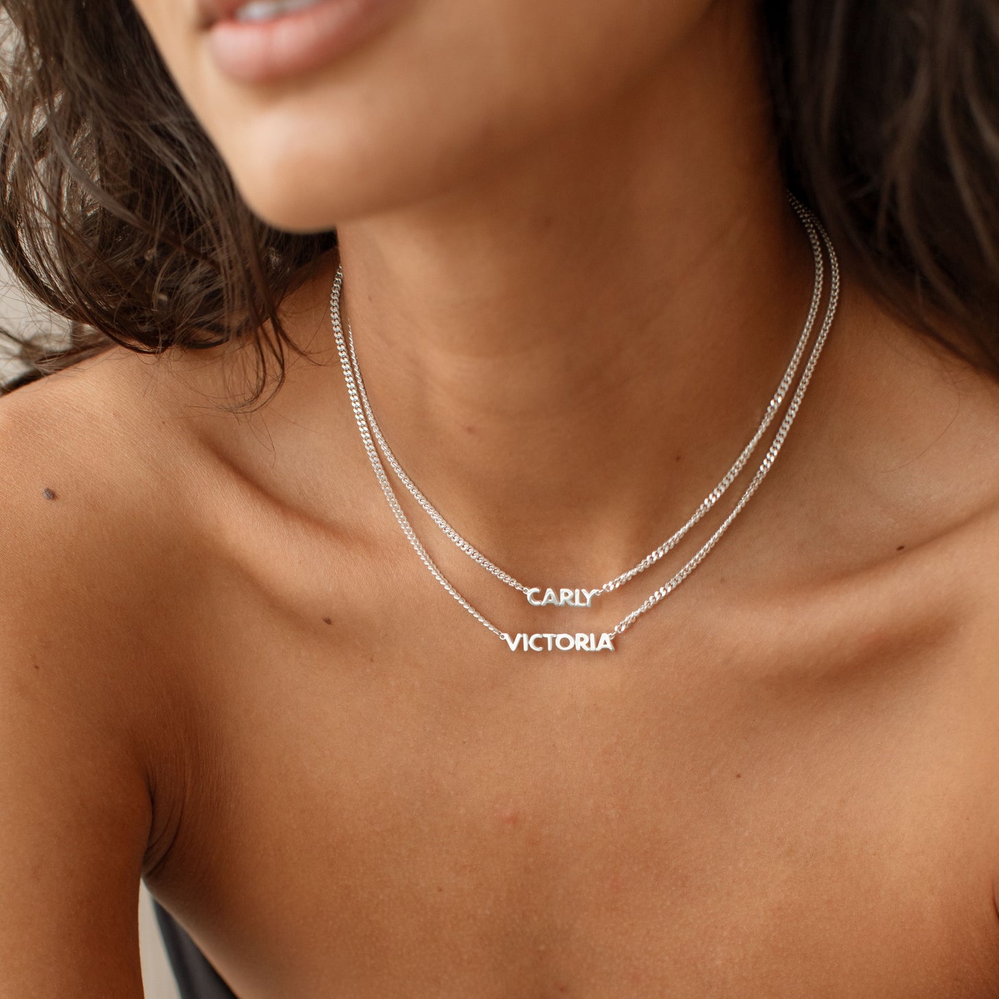 Model wearing 2 silver Nelly Name Necklaces
