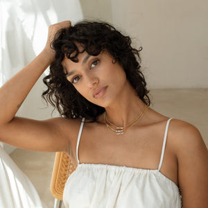 Model wearing 3 Nelly Name Necklaces with white tank top