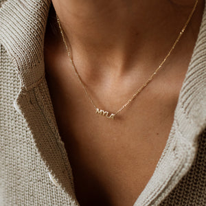 Model wearing gold Noah Name Necklace with figaro chain