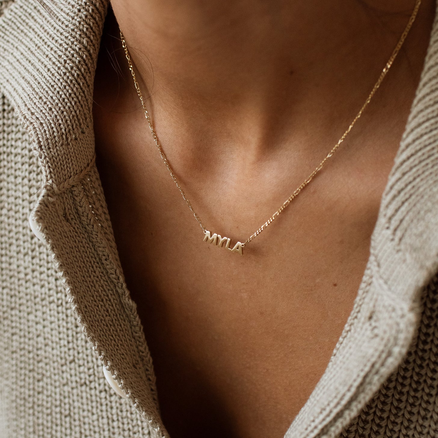 Model wearing gold Noah Name Necklace with figaro chain