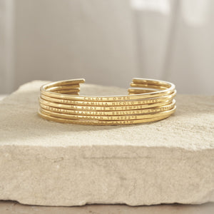 Stacked Rebecca Cuff Bracelets featuring engraved names, messages, and coordinates