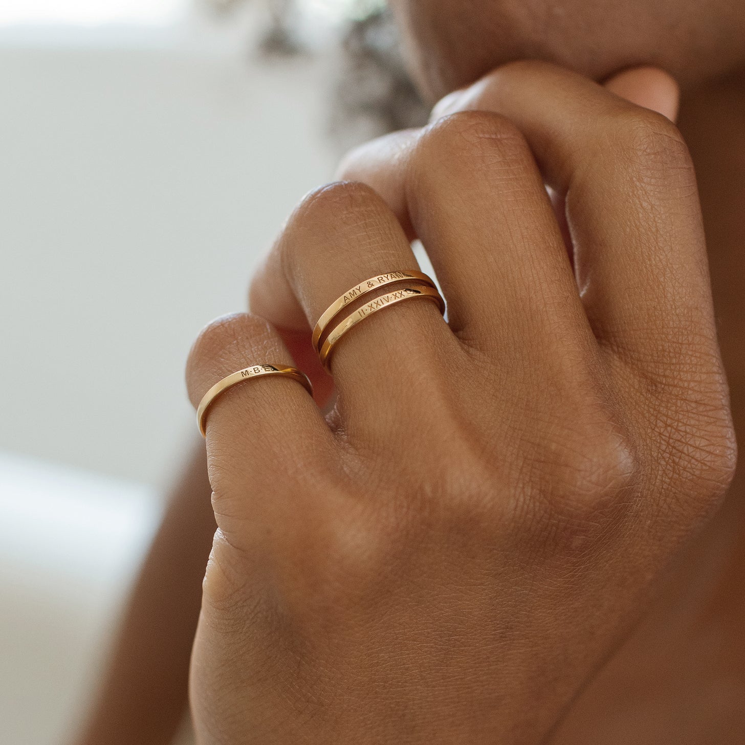 Model wears dainty stackable Rebecca Rings with custom engravings on inner and outer bands