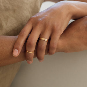 Model wears dainty and stackable Rebecca Engraved Rings, with custom engravings on the outer and inner band