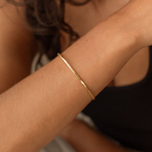 Emerald birthstones featured on a gold cuff bracelet with custom names engraved