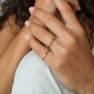 Model wears our Rebecca Rings in gold, featuring custom engraved names and birthstones on the outer and inner band
