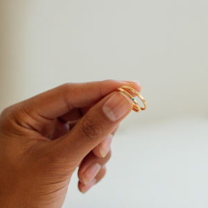 Dainty gold band rings featuring birthstones and personalized engravings on the outer and inner band